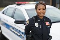 Picture of female, African-American police academy cadet in front of car